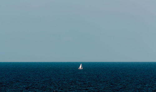 Sailboat sailing on sea against clear sky