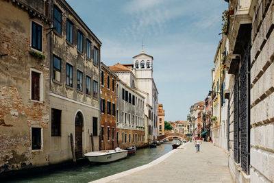 Canal and footpath amidst buildings in city