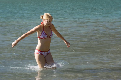 Playful young woman wearing bikini while enjoying in sea