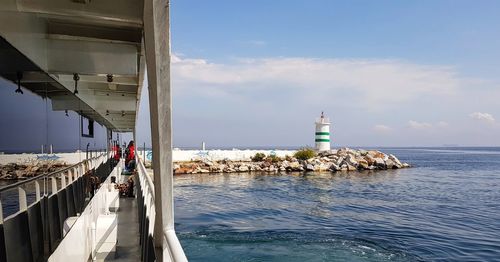 Lighthouse amidst sea and buildings against sky