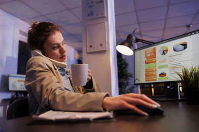 Side view of young woman using laptop at home