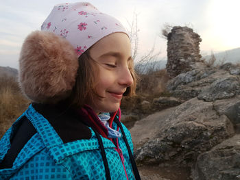 Cute young girl, kid posing with winter ear cap in the outdoors