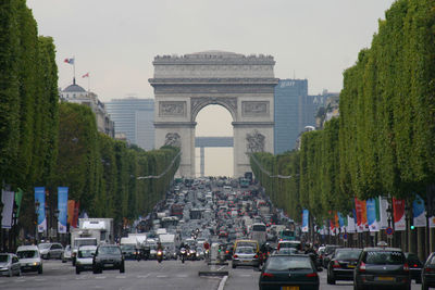 Cars on road against arc de triomphe in city