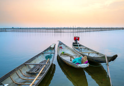 Boat moored in lake against sky during sunset