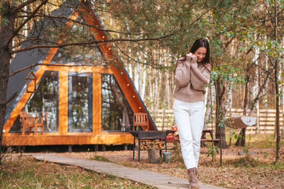 Side view of young woman standing against trees