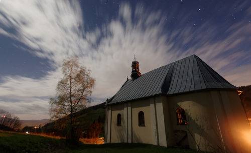 Exterior of house on field against sky at dusk