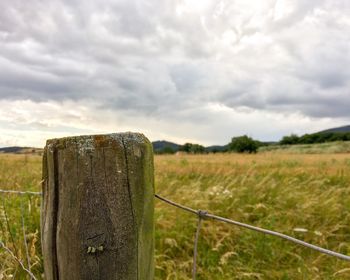 Grassy field against cloudy sky