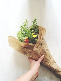 Cropped hand holding bouquet on table