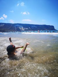 Boy at beach against sky