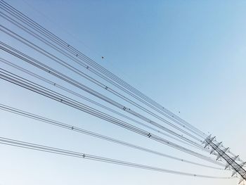 Low angle view of power lines against clear blue sky