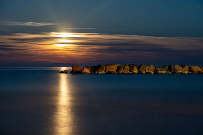 Moonlit sunrise at the sea on a clear sky evening
