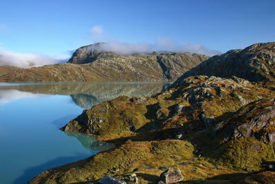 Scenic view of lake and rocks against blue sky