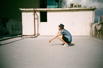 Side view of a man crouching on terrace