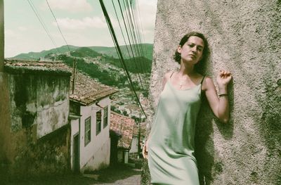 Side view of young woman standing against wall