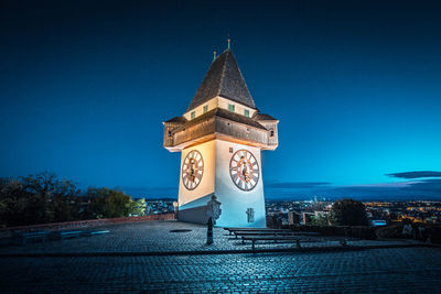 Clock tower against blue sky in city at night