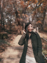 Young woman standing against trees during winter