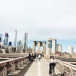 Full length of woman cycling on brooklyn bridge on sunny day