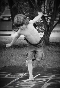 Shirtless boy playing hopscotch at park