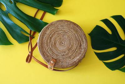 Close-up of leaves and purse on yellow background