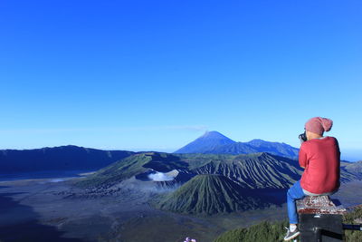 Man standing on mountain against clear blue sky