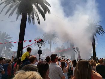 Crowd and smoke against sky