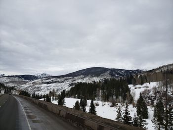 Road by snowcapped mountains against sky during winter