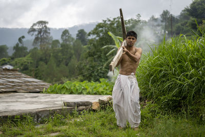 Happy indian farmer standing with wooden plough in rice field