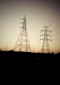 Low angle view of electricity pylon against sky at sunset