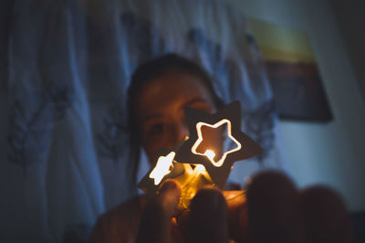 Close-up of woman holding star shape sitting in darkroom