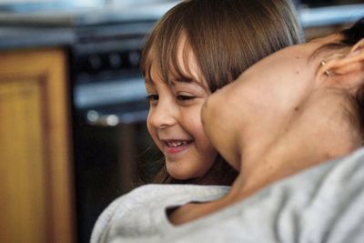 Mother kissing on daughter cheek at home