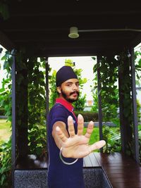 Portrait of young man gesturing while standing in built structure