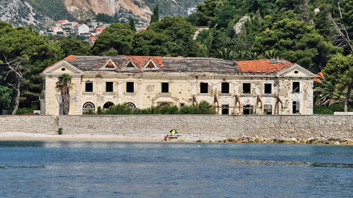 Man by river against built structures