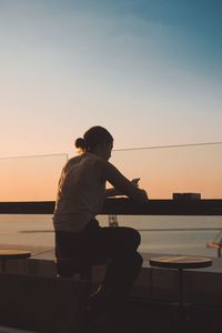 Woman using mobile phone against sky during sunset