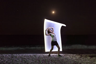 Full length of woman standing against illuminated sky