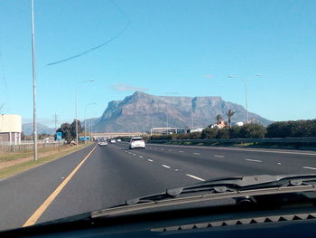 Road by mountains against clear sky