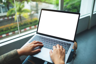 Midsection of woman using laptop at home