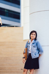 Portrait of young woman standing against wall