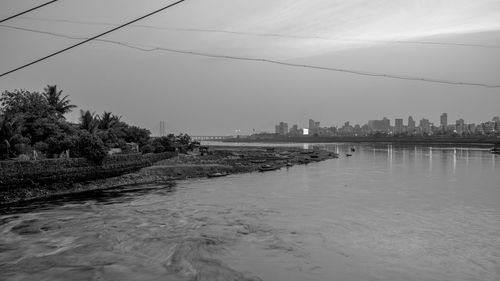 Scenic view of river by buildings against sky