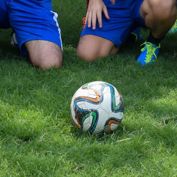 Low section of boys playing soccer on field