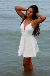 Young woman wearing white dress while standing in sea