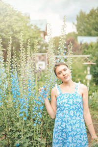 Portrait of smiling young woman standing against plants