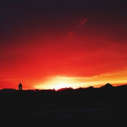 Silhouette person standing against orange sky during sunset