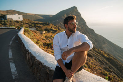 Young man standing on mountain against sky