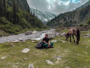 Man sitting on rocks against mountains