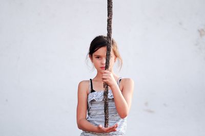 Portrait of beautiful young woman standing against wall