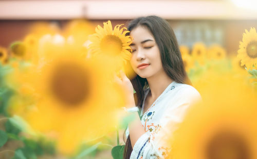 Portrait of beautiful young woman with yellow flower