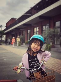 Portrait of girl with bicycle on street in city