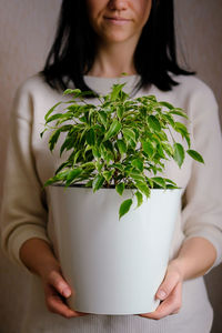 Midsection of woman standing against white wall