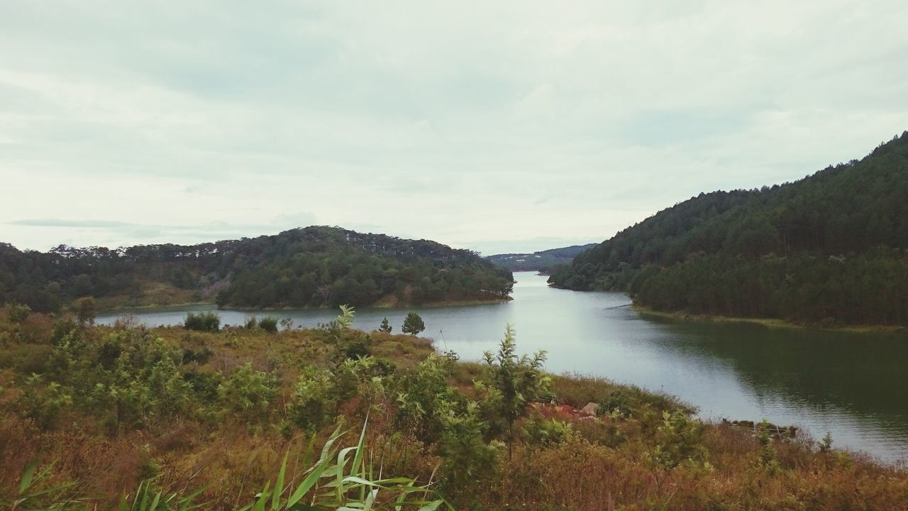 water, mountain, sky, tranquil scene, tranquility, scenics, lake, beauty in nature, cloud - sky, nature, mountain range, landscape, river, cloud, plant, idyllic, non-urban scene, grass, cloudy, day