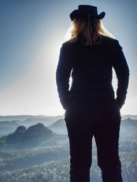 Successful woman hiker cheking the altitude on the top of sandstone sharp cliff edge.